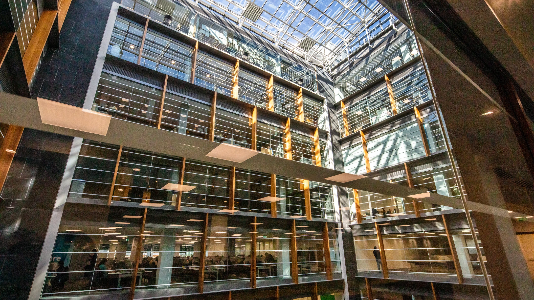Looking upwards at the building's office space floors, each with glass windows.
