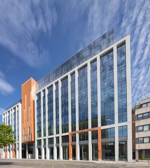 Outside of building with the sunny blue sky and white clouds reflecting in the windows.