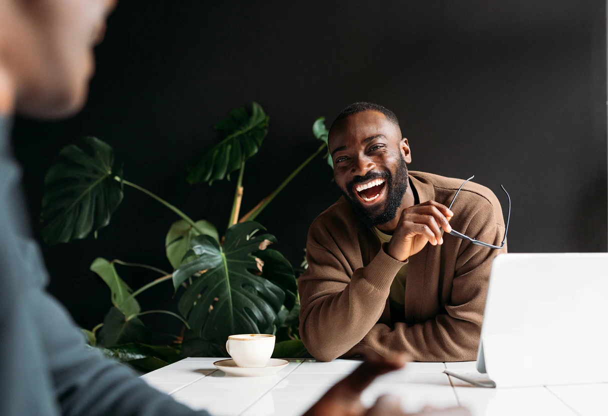 Man laughing with colleague in a workspace meeting