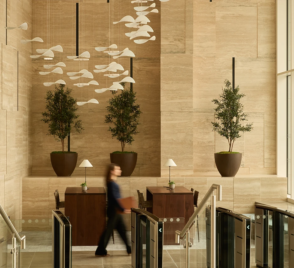 High ceiling lobby area with woman walking past the entry barriers.