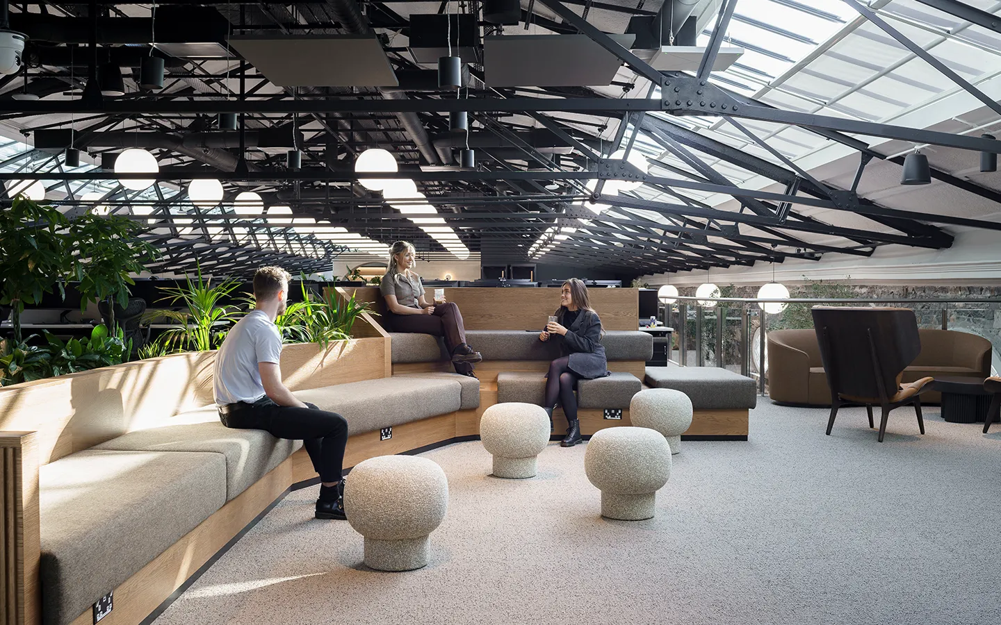 Three people talking in a workspace breakout with coffees