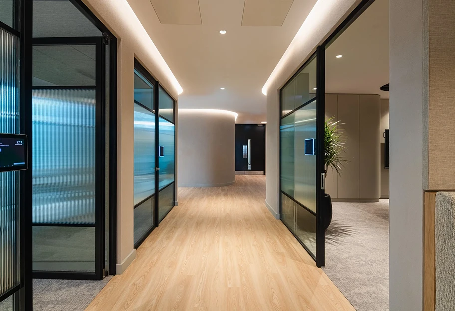 Wooden floored corridor with meeting rooms lining each side.