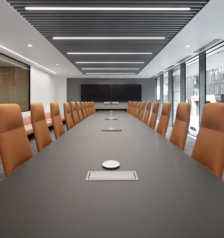 Meeting room looking down a long table with brown chairs lining each side.