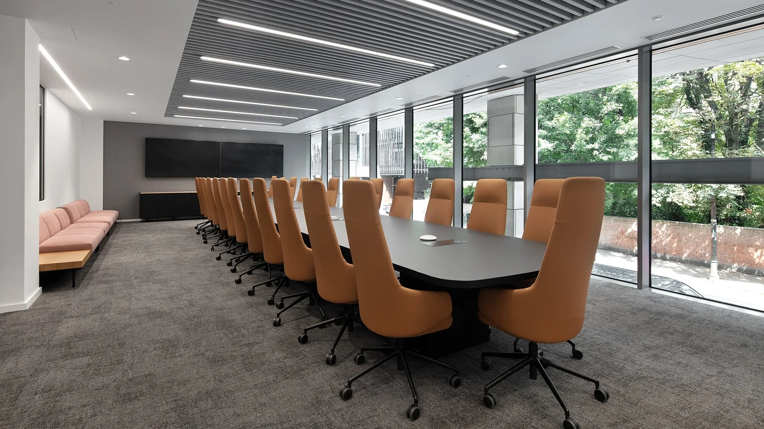 Meeting room with a long desk with brown leather chairs on either side.