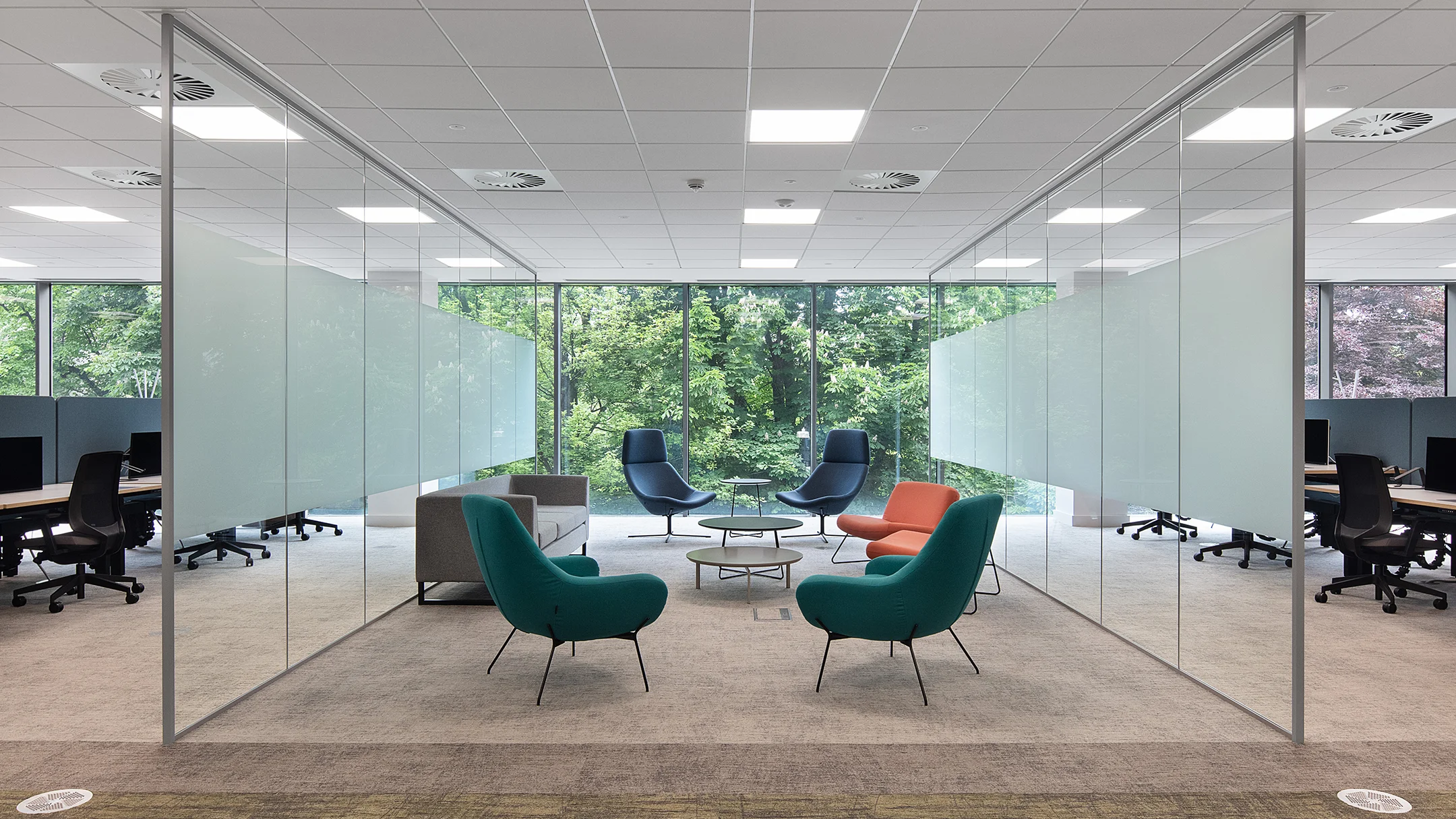 Glass walled workspace with a window showing trees from outside.