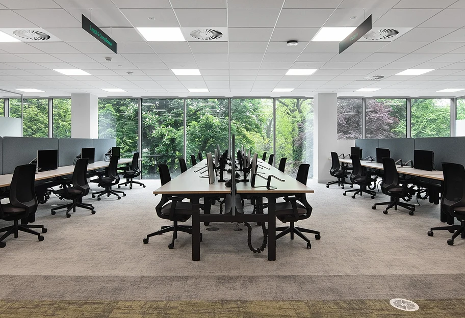 Workspace floor with rows of desks overlooking a park.