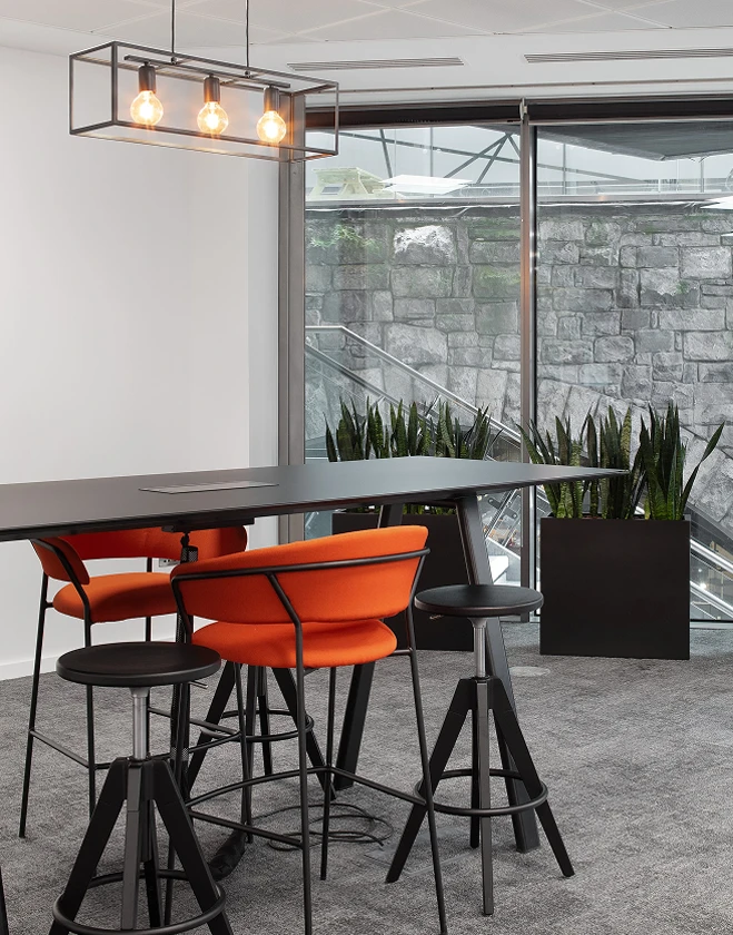 Table and orange chairs with hanging light above.