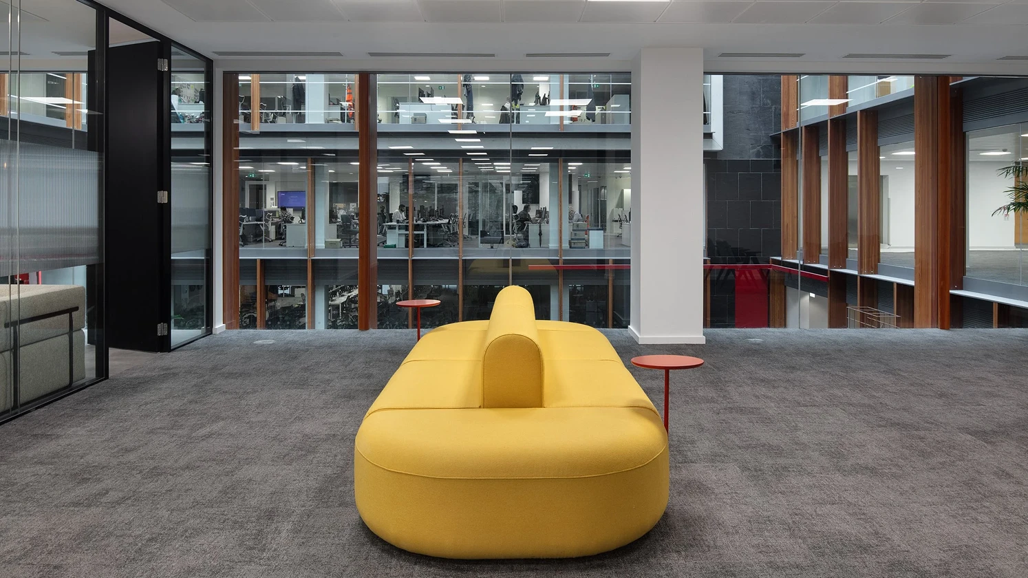 Yellow couch by a window overlooking floors of workspaces.