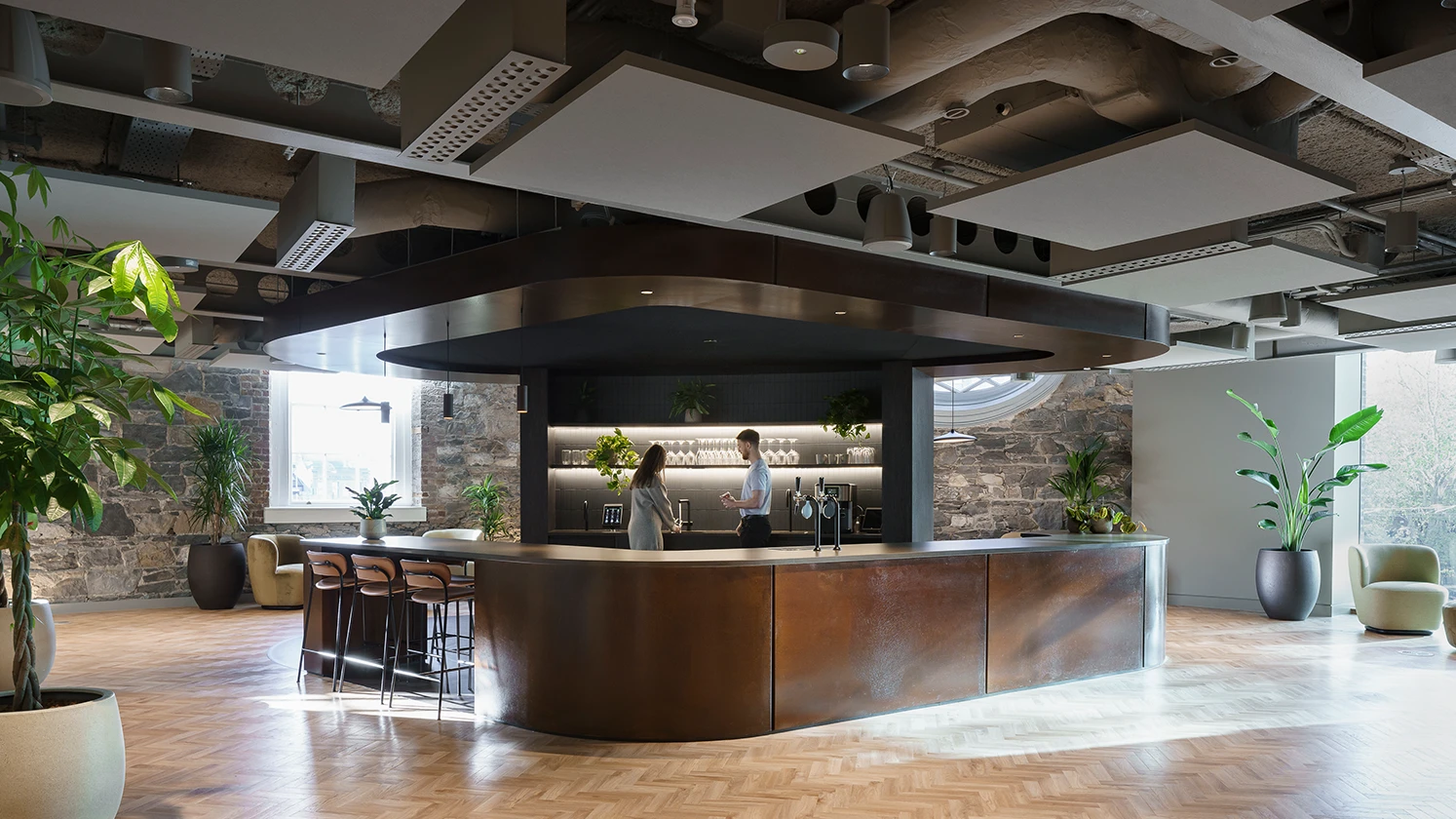 Long wooden kitchen island with two people talking at it.