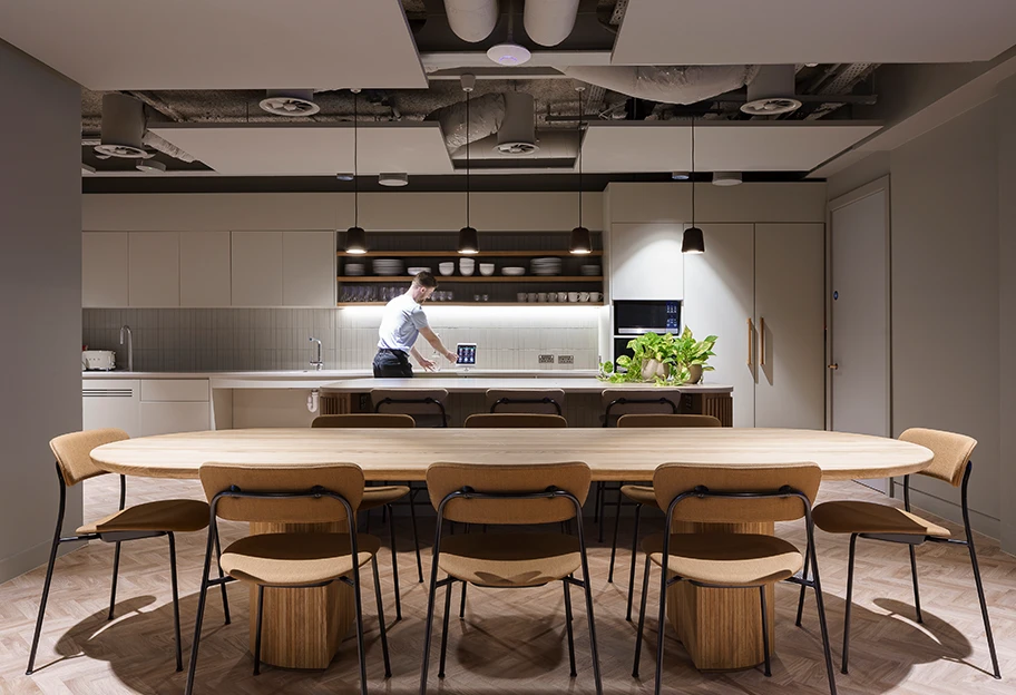 Man getting water from sink in workspace kitchen.