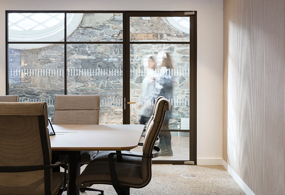 Women walking by an meeting room window.