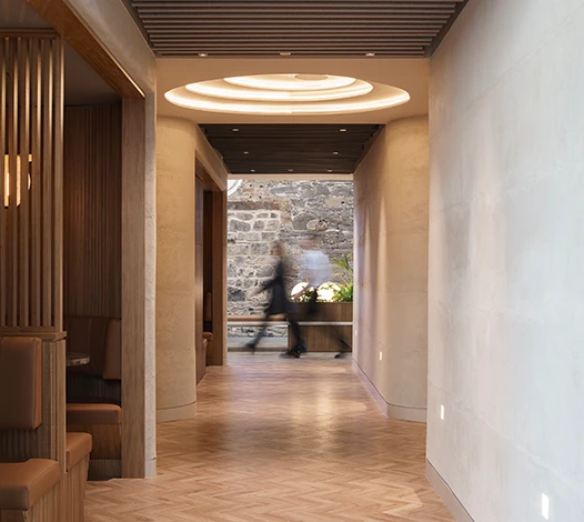 Blurred silhouttes at the end of a nicely lit hallway, with work cubicles lining the left wall.